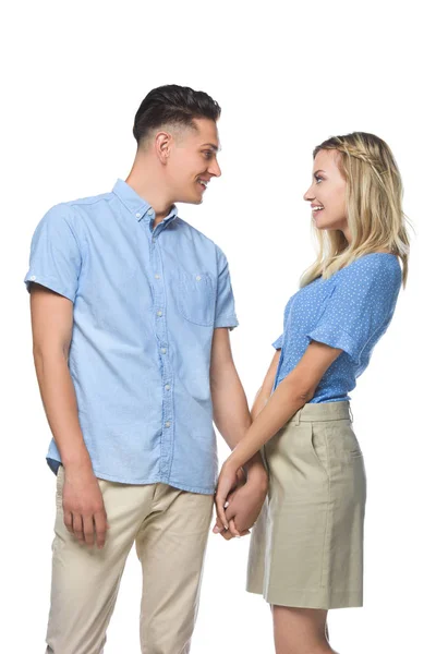 Smiling couple in blue shirts holding hands and looking at each other isolated on white — Stock Photo