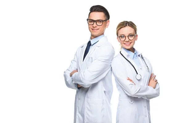 Médicos sonrientes de pie con los brazos cruzados y mirando a la cámara aislada en blanco - foto de stock