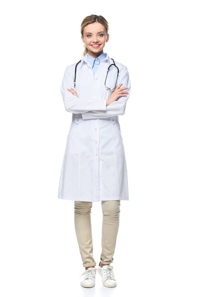 Young female doctor in white coat posing with crossed arms, isolated on white — Stock Photo