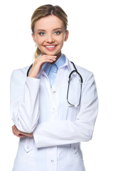 Lächelnde junge Ärztin in weißem Mantel mit Stethoskop, isoliert auf weiß — Stockfoto