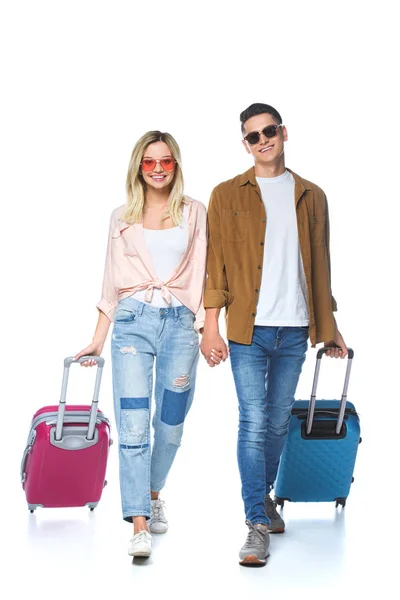 Jeune couple heureux tenant la main et marchant avec des valises isolées sur blanc — Photo de stock