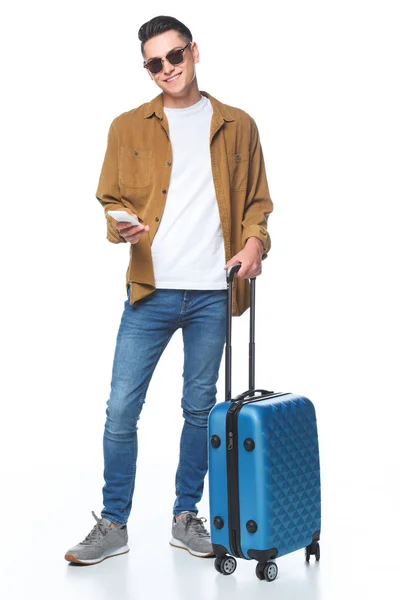Glücklicher junger Mann mit Gepäck und Smartphone isoliert auf weiß — Stockfoto