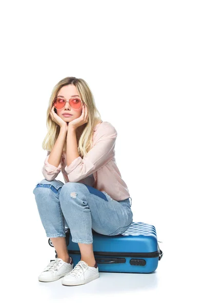 Jovem mulher entediada sentado na bagagem isolada no branco — Fotografia de Stock