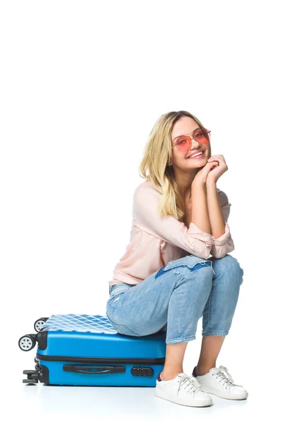 Joven feliz mujer sentado en equipaje aislado en blanco - foto de stock
