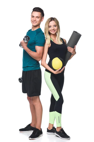 Jovem casal desportivo com vários equipamentos olhando para a câmera isolada no branco — Fotografia de Stock