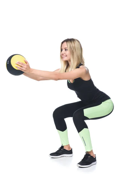 Sporty giovane donna che fa squat con palla medicina isolato su bianco — Foto stock