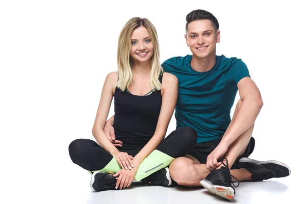 Jovem casal desportivo em sportswear sentado no chão isolado no branco — Fotografia de Stock