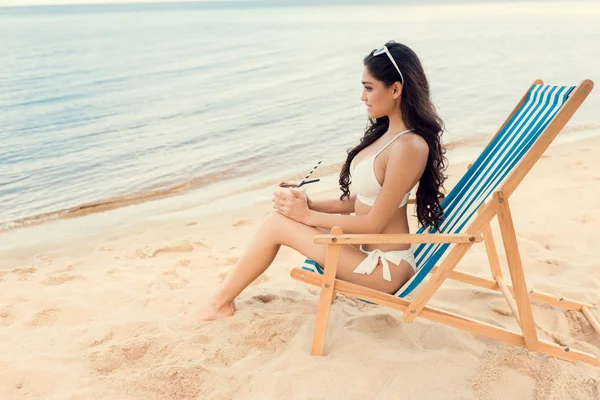 Schöne junge Frau mit grünem Kokosgetränk am Sandstrand — Stockfoto