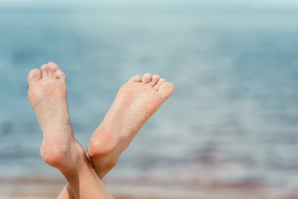 Vista recortada de mujer descalza en la playa cerca del mar - foto de stock