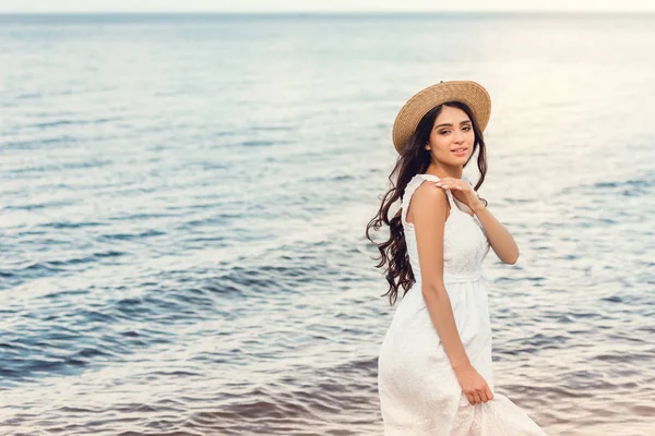 Attraktives Mädchen mit Strohhut, das im Sommer am Meer spazieren geht — Stockfoto