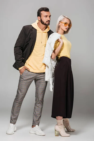 Joven pareja elegante posando en trajes de otoño sobre fondo gris - foto de stock