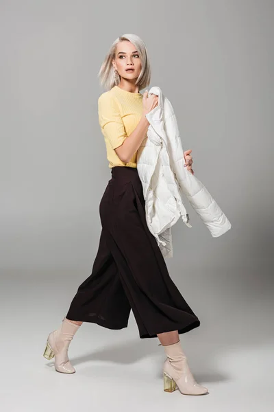 Jovem modelo feminino atraente com jaqueta de outono branco no fundo cinza — Fotografia de Stock