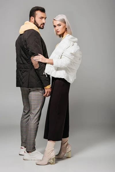 Модные мужские и женские модели в стильных осенних нарядах, позирующие на сером фоне — стоковое фото