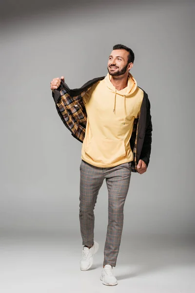 Glücklicher junger Mann in stylischer Herbstjacke posiert auf grauem Hintergrund — Stockfoto