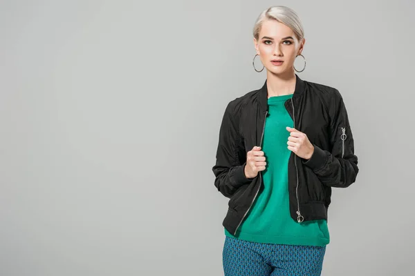 Fashionable young female model in black jacket posing isolated on grey background — Stock Photo