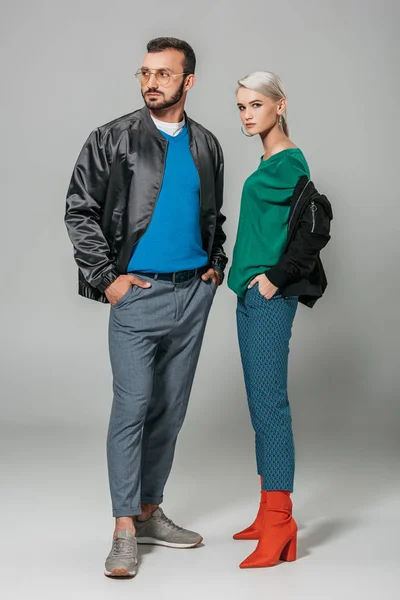 Pareja de modelos de moda en trajes de otoño con estilo sobre fondo gris - foto de stock