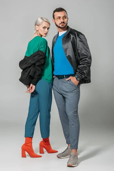 Young couple of models in stylish autumn jackets on grey background — Stock Photo