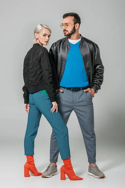 Stilvolles männliches Modell posiert mit Händen in Taschen in der Nähe der schönen Freundin auf grauem Hintergrund — Stockfoto