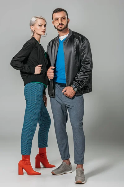 Stylish couple of models posing in black jackets on grey background — Stock Photo