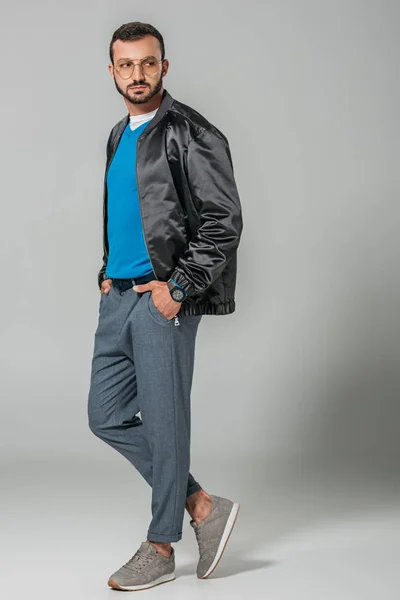 Junge bärtige männliche Modell in stilvollem Outfit schaut weg auf grauem Hintergrund — Stockfoto