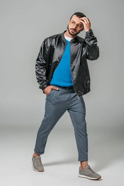 Modèle masculin à la mode en tenue d'automne posant avec la main dans la poche sur fond gris — Photo de stock