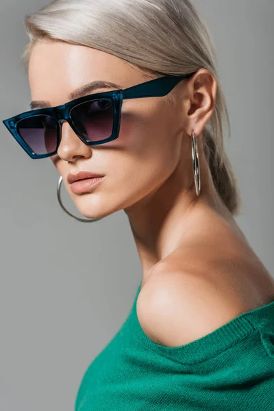 Modèle féminin élégant dans les lunettes de soleil en regardant la caméra isolée sur fond gris — Photo de stock