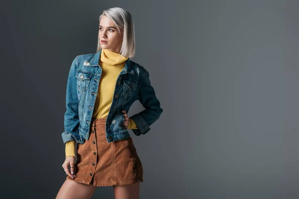 Attractive woman posing in yellow turtleneck, trendy corduroy skirt and jeans jacket, isolated on grey — Stock Photo