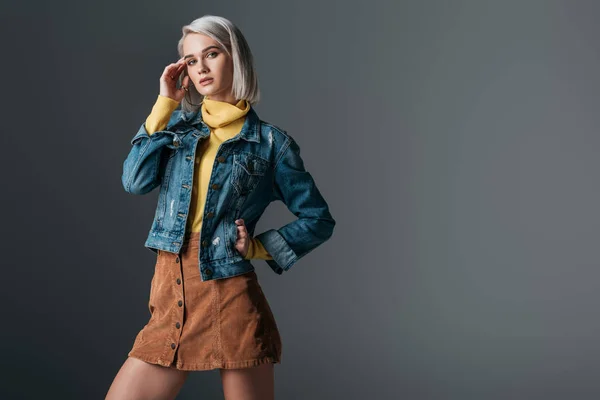 Femme posant en col roulé jaune, jupe en velours côtelé tendance et veste en jean, isolée sur gris — Photo de stock