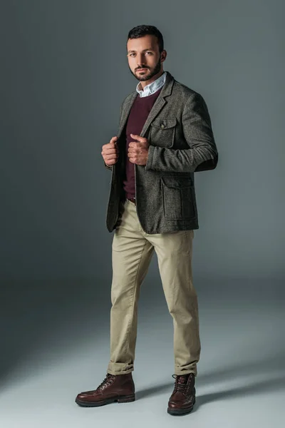 Handsome male model posing in beige pants and tweed jacket, on grey — Stock Photo