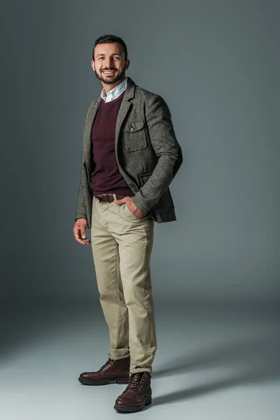 Elegant male model posing in beige pants and tweed jacket, on grey — Stock Photo