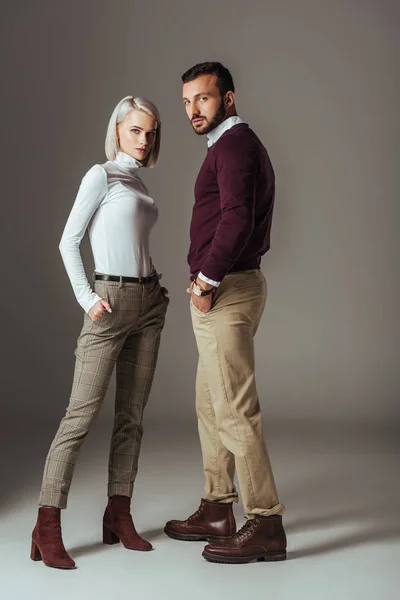 Couple of models posing in stylish autumn outfit, on grey — Stock Photo