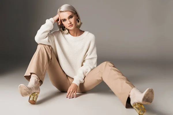 Модная модель, позирующая в белых свитерах, бежевых брюках и на осенних каблуках, на сером — стоковое фото