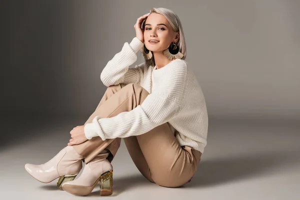 Elegante mujer de moda posando en suéter blanco y tacones de otoño, en gris - foto de stock