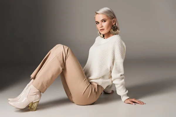 Stylish beautiful girl posing in white sweater and autumn heels, on grey — Stock Photo