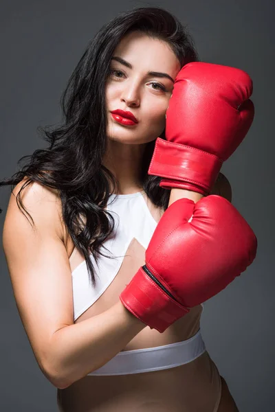 Sexy sportive woman in white sportswear showing boxing gloves isolated on grey — Stock Photo