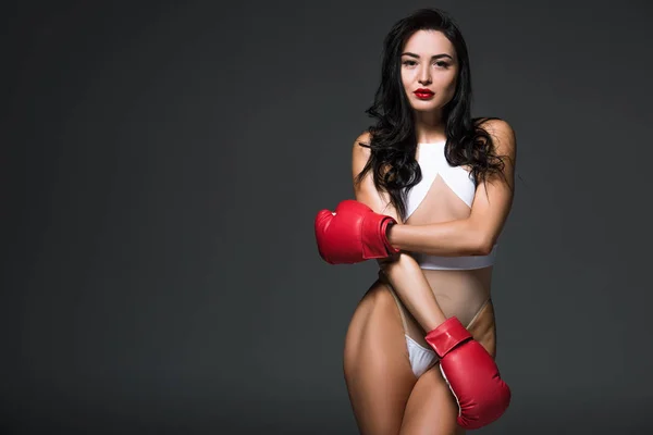 Mulher esportiva sedutora em roupa de banho branca e luvas de boxe isoladas em cinza — Fotografia de Stock