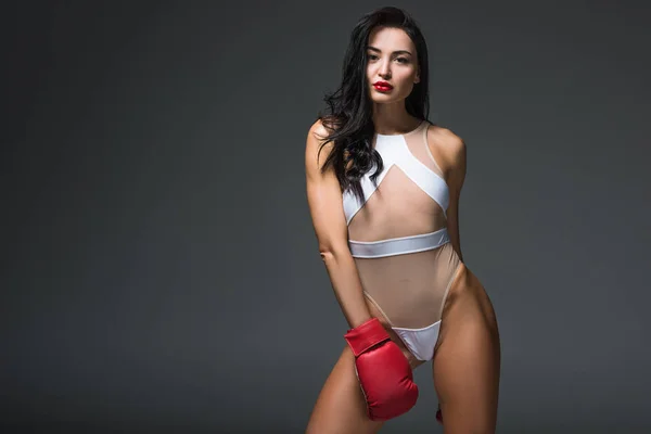 Sexy sportliche brünette Frau in weißer Badebekleidung und Boxhandschuh isoliert auf grau — Stockfoto