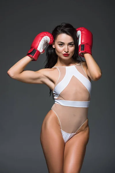 Sexy esportiva mulher posando em branco swimwear e luvas de boxe isolado no cinza — Fotografia de Stock