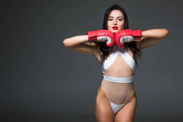 Sexy sportive woman in white leotard and boxing gloves isolated on grey — Stock Photo