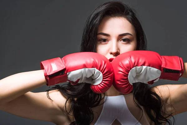Женщина в боксёрских перчатках смотрит на камеру, изолированную на сером — стоковое фото