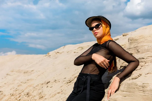 Beautiful fashionable woman posing near sand dune — Stock Photo