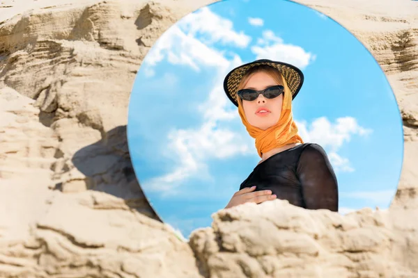 Espelho redondo com reflexão de belo modelo elegante em chapéu e óculos de sol — Fotografia de Stock