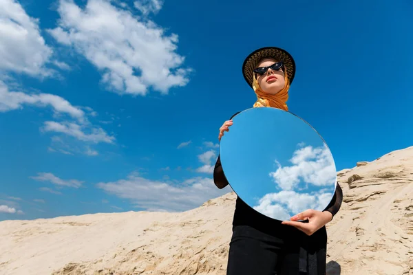 Élégant attrayant fille posant avec miroir rond et reflet du ciel nuageux — Photo de stock