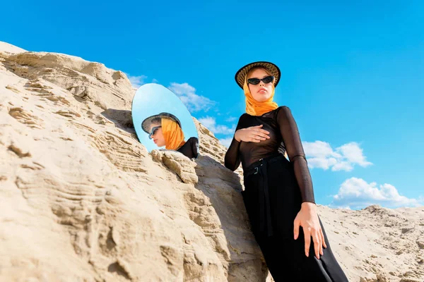 Elegante bela mulher posando perto de duna de areia com espelho — Fotografia de Stock