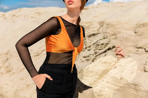 Vista cortada de mulher em roupas de moda preto segurando espelho com reflexão de duna de areia — Fotografia de Stock