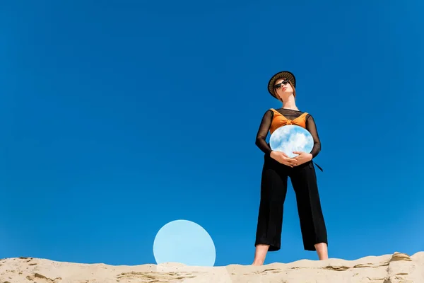 Attraente ragazza elegante in abiti alla moda in posa con specchi rotondi con riflesso del cielo blu — Foto stock