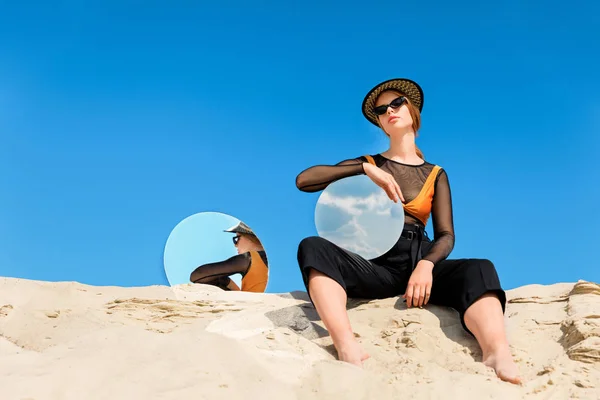 Modelo elegante posando con espejos redondos con reflejo del cielo azul - foto de stock