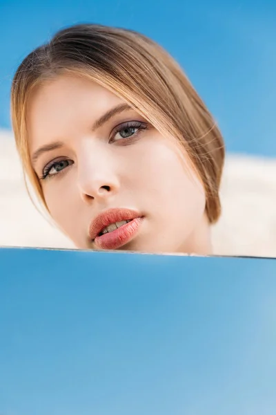 Menina loira atraente posando perto do espelho com reflexo do céu azul — Fotografia de Stock