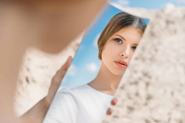 Красива дівчина тримає шматок дзеркала і дивиться на її відображення — стокове фото