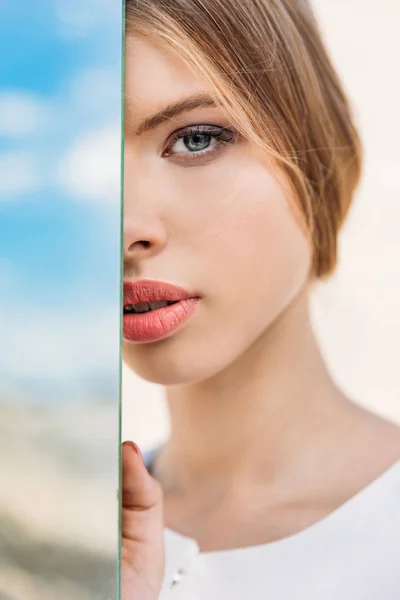 Menina atraente posando perto do espelho com reflexo do céu — Fotografia de Stock